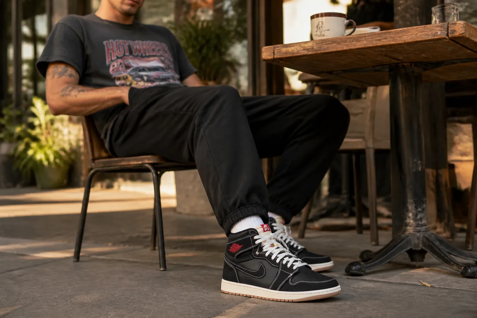 Lifestyle photo of Nike Total 90 worn with joggers and a graphic tee, captured in an outdoor cafe setting with warm lighting