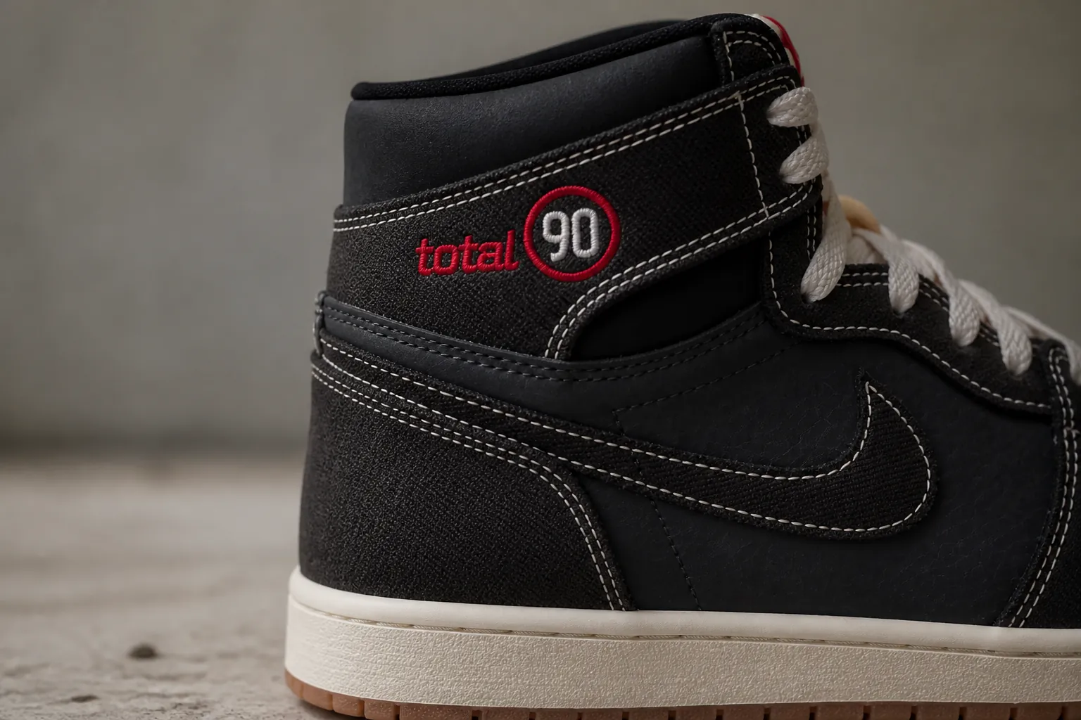 Detail shot of the embroidered Total 90 logo showing precise stitching in accent color on the sneaker heel counter