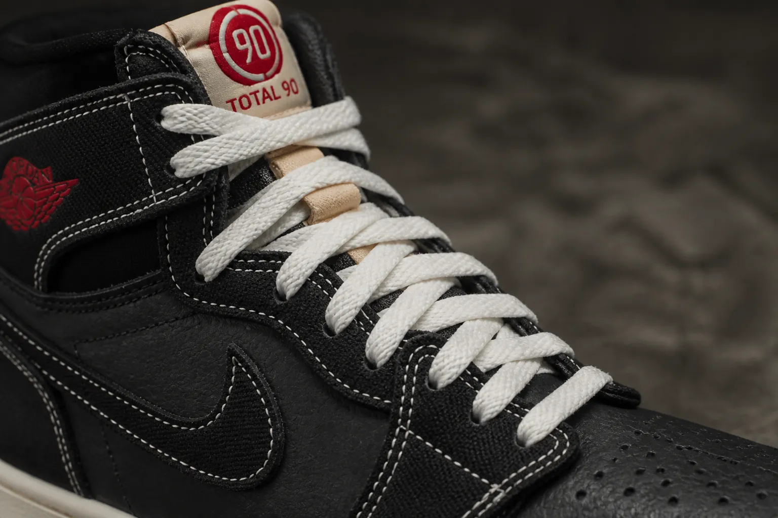 Detailed view of the Nike Total 90 asymmetrical lacing system showing offset lace holes and premium flat laces against dark background