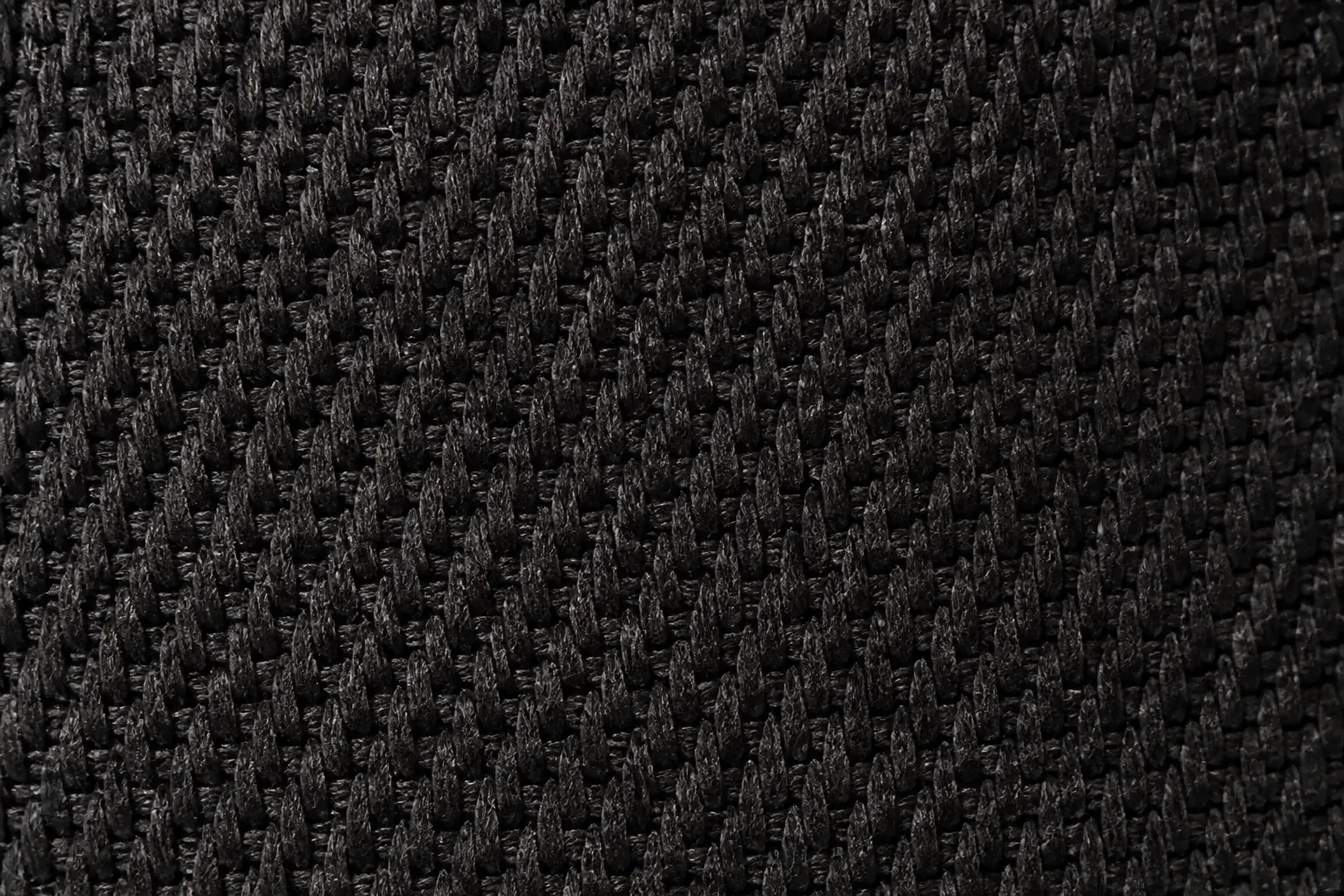 Close-up macro shot of the black woven textile upper texture showing intricate weave pattern with premium quality threads and durability