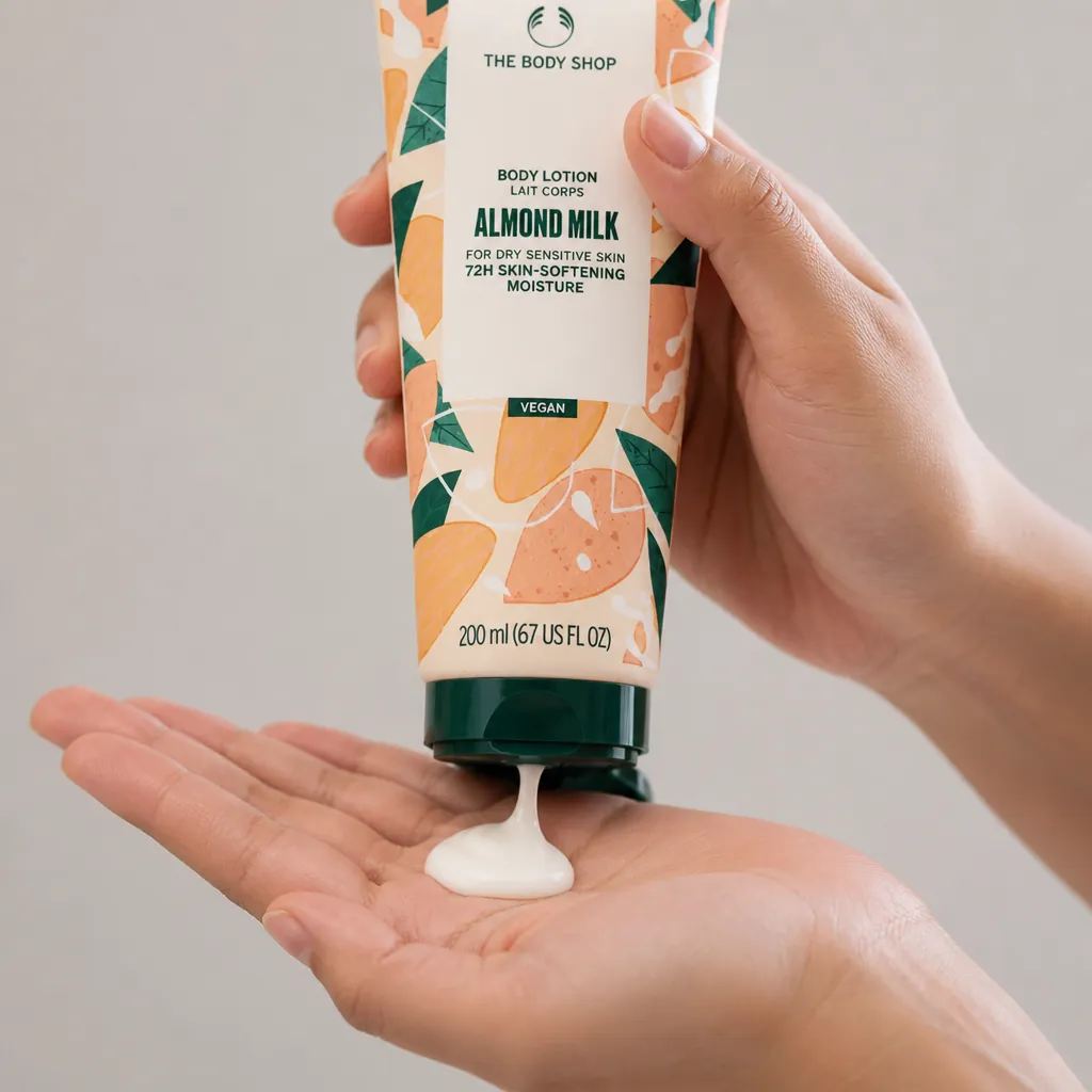 Squeezing almond milk lotion from tube into palm, creamy white product visible