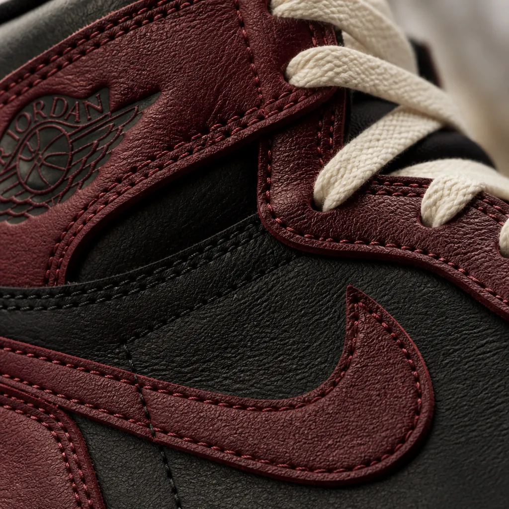 Close-up macro shot of premium leather texture showing the fine grain and quality of the Air Jordan 1 High OG Flight Club upper with rich burgundy and black colorway