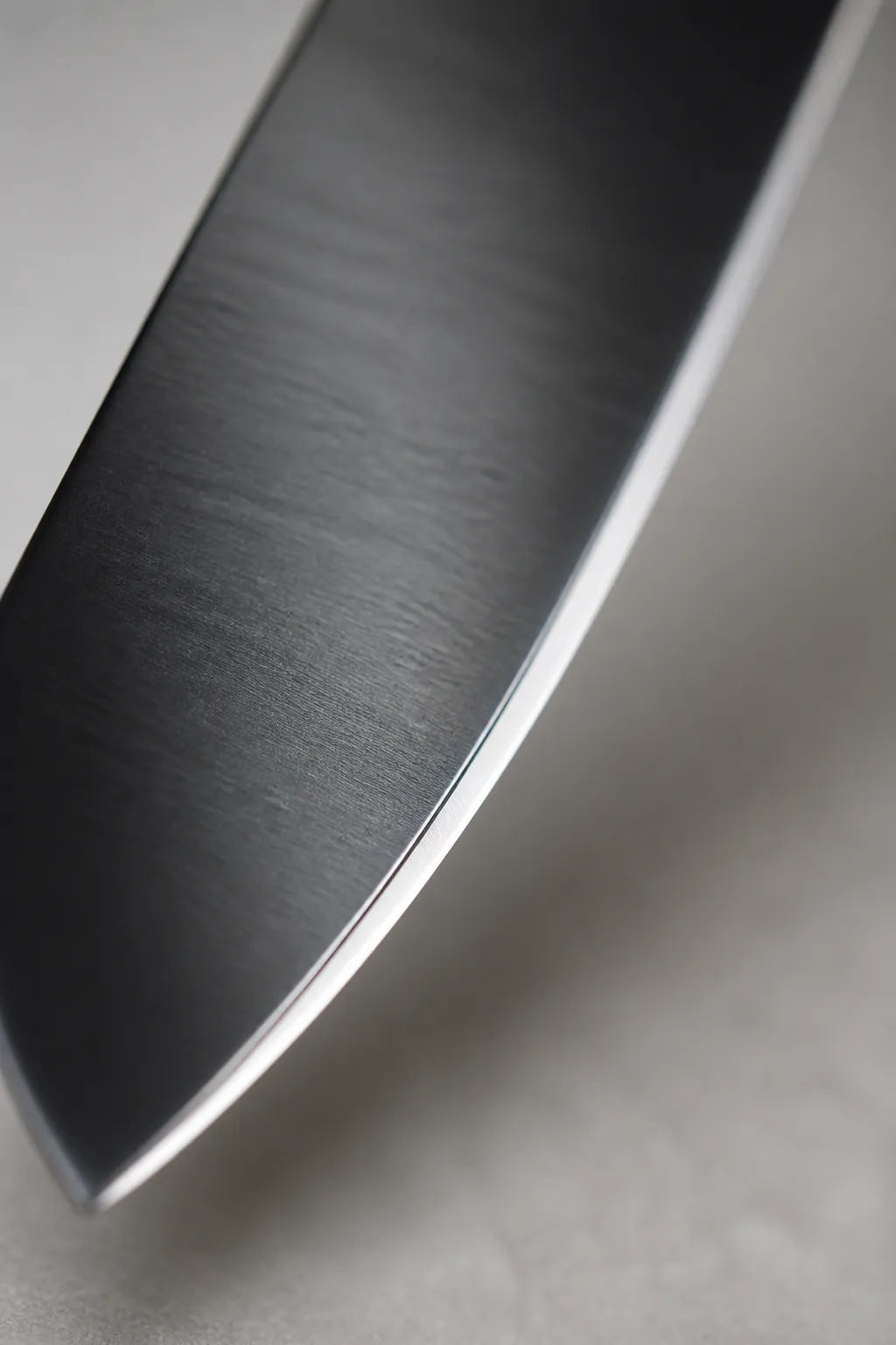 Extreme close-up macro photograph of a kitchen knife blade showing the precision-ground edge and mirror-polished high-carbon stainless steel surface