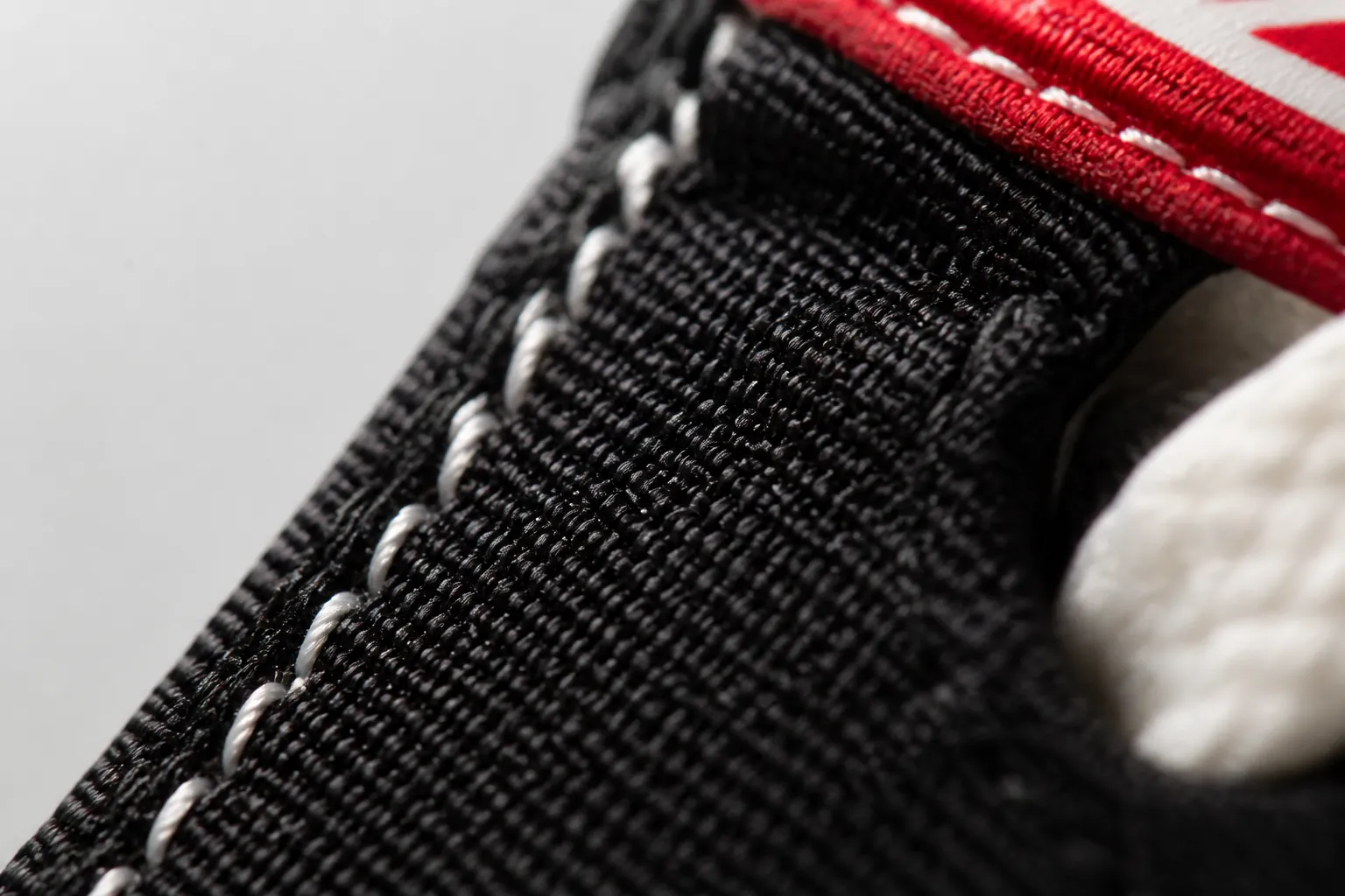 Extreme close-up macro photograph of premium black woven textile upper texture showing intricate weaving pattern with visible depth and quality construction